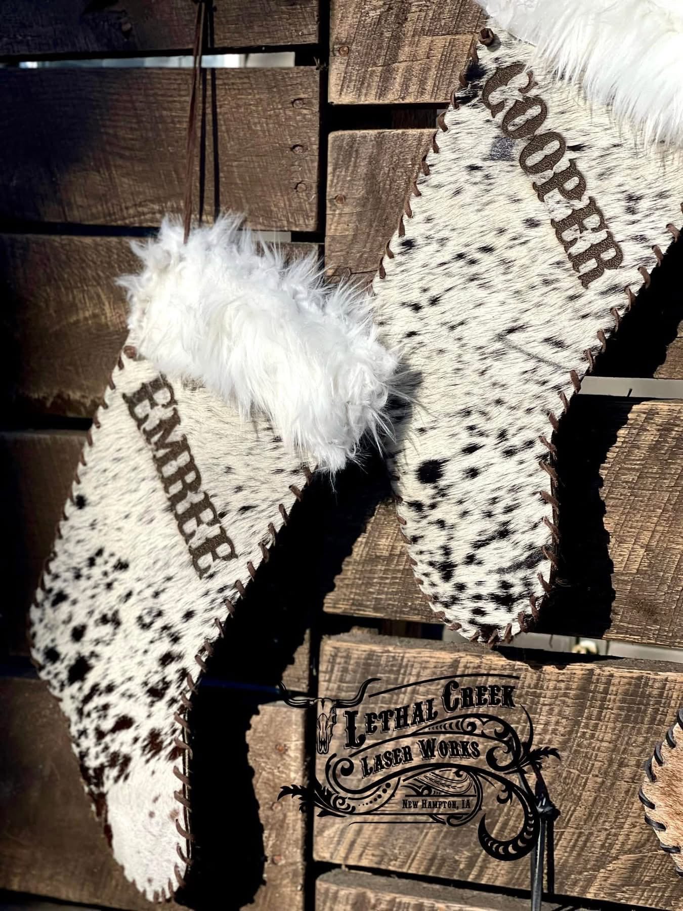 Black and white personalized cowhide Christmas stocking with leather stitching and fluffy fur top